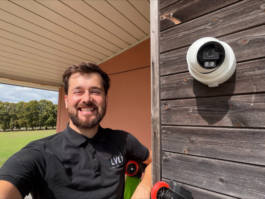 LVL1 engineer beside a newly installed Hikvision CCTV camera mounted on the outside of a school building.