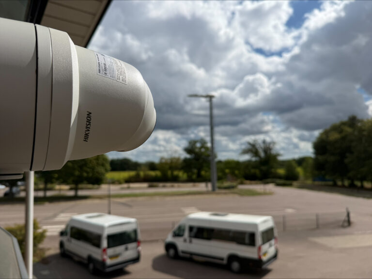 Hikvision CCTV camera installed overlooking a large outdoor area at a school site.